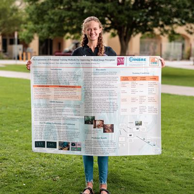 IMAGE DESCRIPTION Woman holding a research project poster