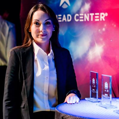 Head and shoulders of a woman standing next to a table with awards