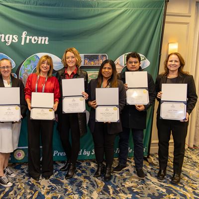 IMAGE DESCRIPTION A group of seven women and one man standing holding certificates