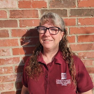 Head and shoulders of a woman standing next to a brick wall