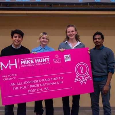 Four people holding an oversized check