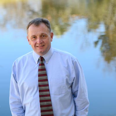 Man standing outdoors in front of a pond
