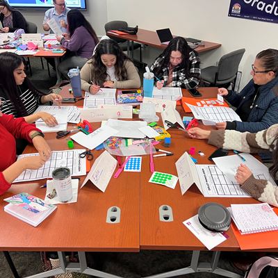 IMAGE DESCRIPTION A group of women seated at a table with various stationary supplies