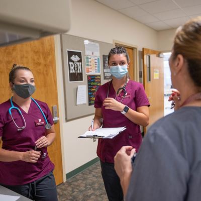 IMAGE DESCRIPTION Two nursing students speaking with a professor