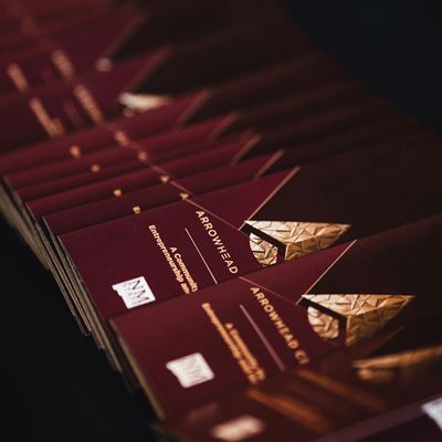 IMAGE DESCRIPTION A row of programs with gold foil lettering on a table