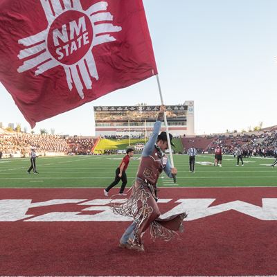 IMAGE DESCRIPTION A man dressed as Pistol Pete waves a flag on a football field