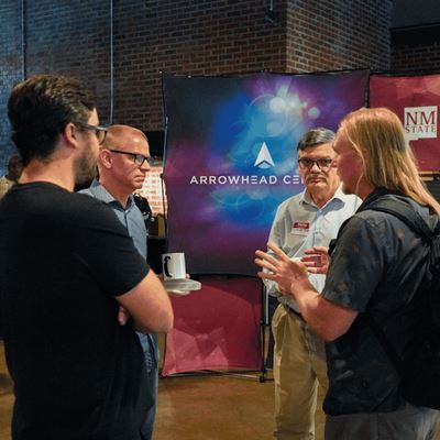 IMAGE DESCRIPTION Four people standing in an event area having a discussion