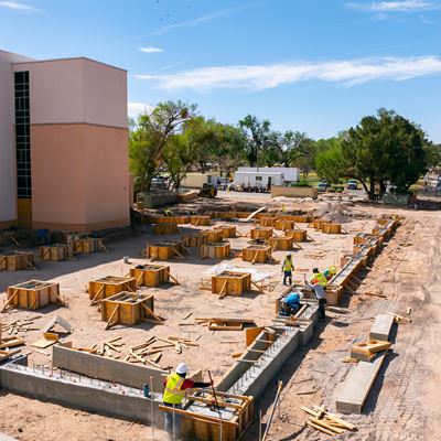 IMAGE DESCRIPTION Construction workers pouring cement outside of a building