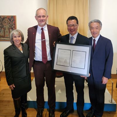 Four people pose with a framed document From left to right New Mexico Gov Michelle Lujan Grisham NMSU President Valerio Ferme Fujitsu Vice President Yoichi Murakami and Japanese Ambassador to the U S Shigeo Yamada
