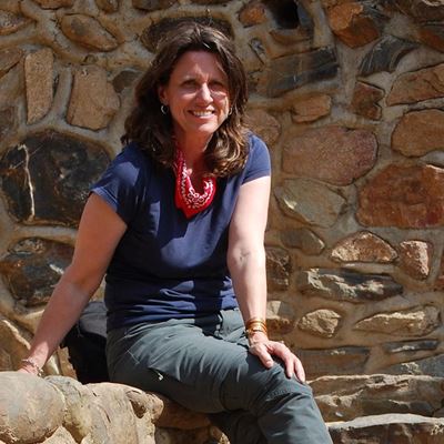 Woman sitting on a rock next to a stone fence