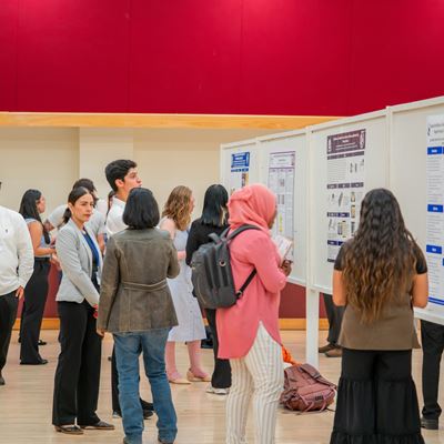 DESCRIPTION In a large room students present research posters to other students faculty and staff