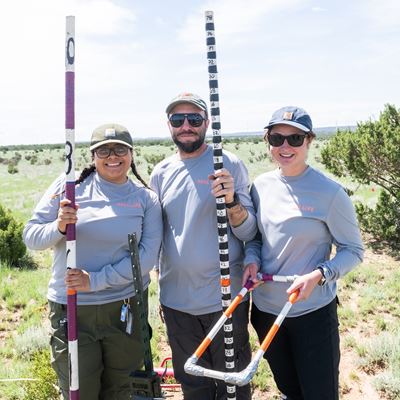 Three people standing outdoors with research equipment