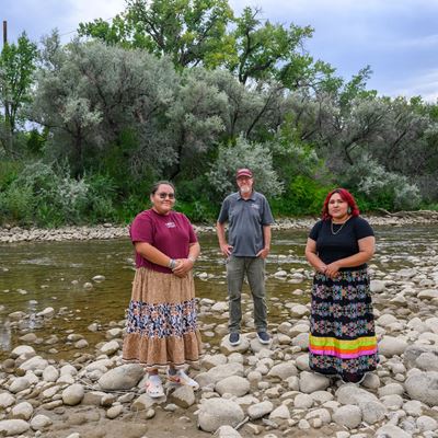 Three people standing on rocks near a river