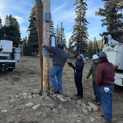 IMAGE DESCRIPTION Four men installing a device on a wooden pole