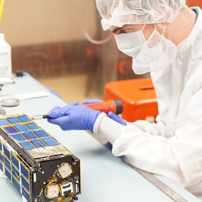 Description A student works on a nano satellite inside a cleanroom in the Klipsch School of Electrical and Computer Engineering