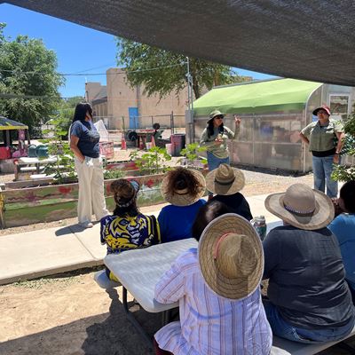 IMAGE DESCRIPTION A woman speaking to a group of people outdoors