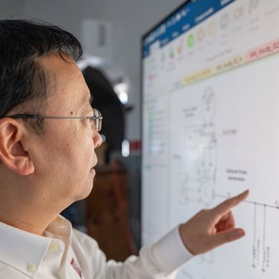 IMAGE DESCRIPTION Man standing next to a screen with diagrams