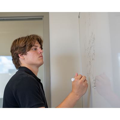 Photo description A student works on his homework on a whiteboard