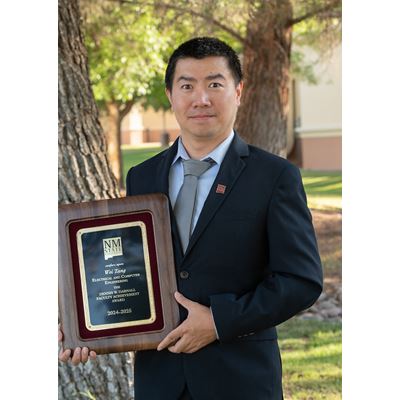 IMAGE DESCRIPTION Man standing outdoors holding a plaque