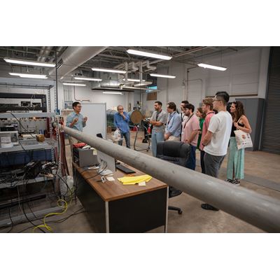 Description A group of people listens to a speaker presenting in a laboratory