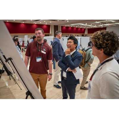 Description Three people stand in front of a research poster board smiling
