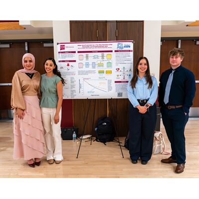 Description Four students stand in front of their poster presentation