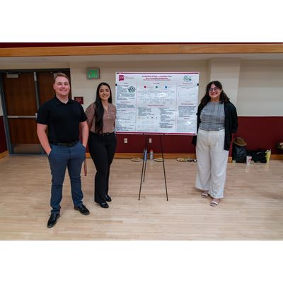 Description Three students stand in front of their poster presentation