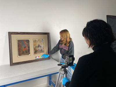 Two women taking photos of paintings