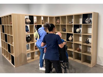 Three people looking at pottery