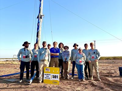 Description The team stands with their safety check lead in front of the rocket they built