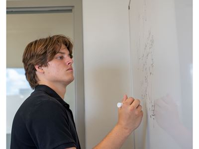 Photo description A student works on his homework on a whiteboard