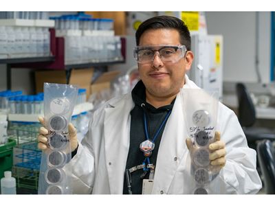 Description A researcher holds up two plastic packs full of Petri dishes that contain filters