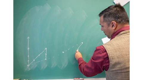 A man writing on a chalkboard