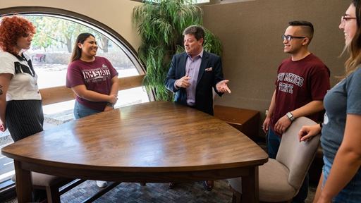 Photo of Dean Bryan Ashenbaum with students at College of Business Complex