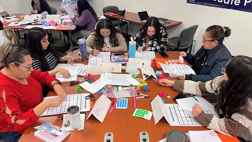 IMAGE DESCRIPTION A group of women seated at a table with various stationary supplies