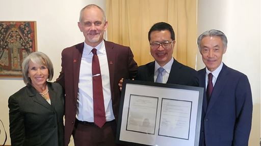 Four people pose with a framed document From left to right New Mexico Gov Michelle Lujan Grisham NMSU President Valerio Ferme Fujitsu Vice President Yoichi Murakami and Japanese Ambassador to the U S Shigeo Yamada