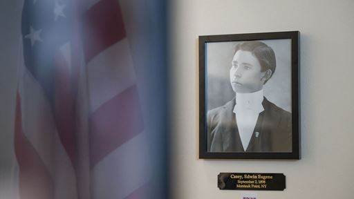 An American flag is seen in the reflection beside a black and white photo of a solder from the Spanish American War