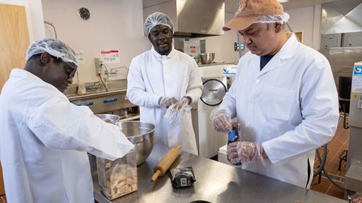 IMAGE DESCRIPTION Three men in a laboratory opening food products to make ice cream