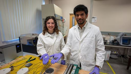 Description A professor and student hold scrap metal parts in a lab where they melt and reuse the metal