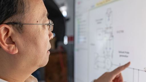 IMAGE DESCRIPTION Man standing next to a screen with diagrams