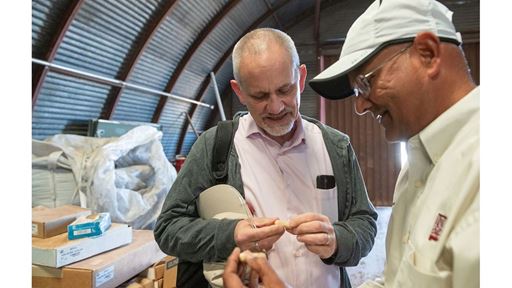 IMAGE DESCRIPTION A man examining a peanut while speaking to another man
