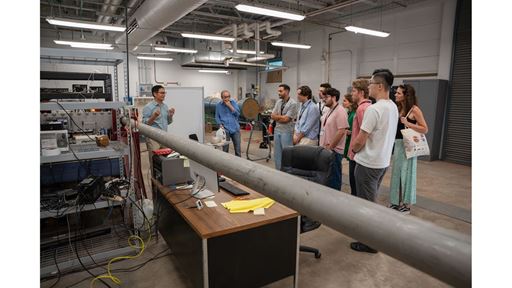 Description A group of people listens to a speaker presenting in a laboratory