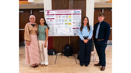 Description Four students stand in front of their poster presentation
