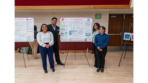 Description Four students stand in front of their poster presentation