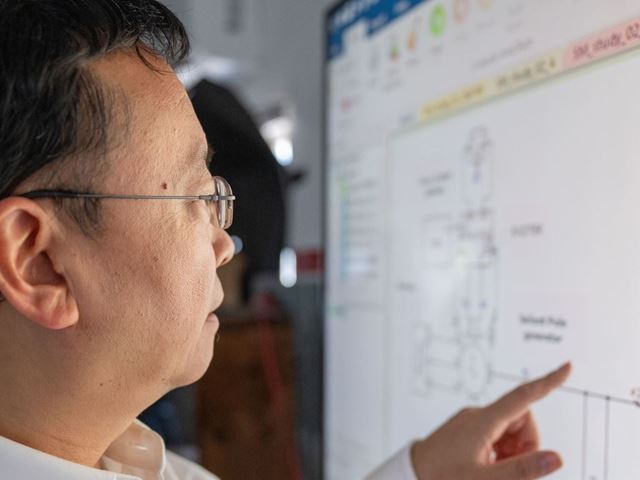 IMAGE DESCRIPTION Man standing next to a screen with diagrams