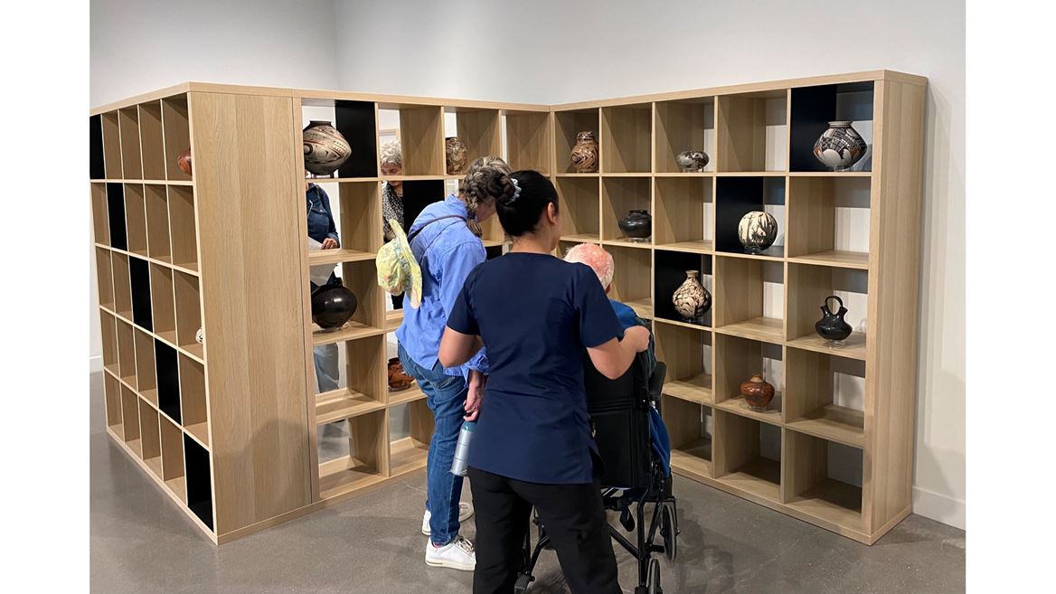 Three people looking at pottery