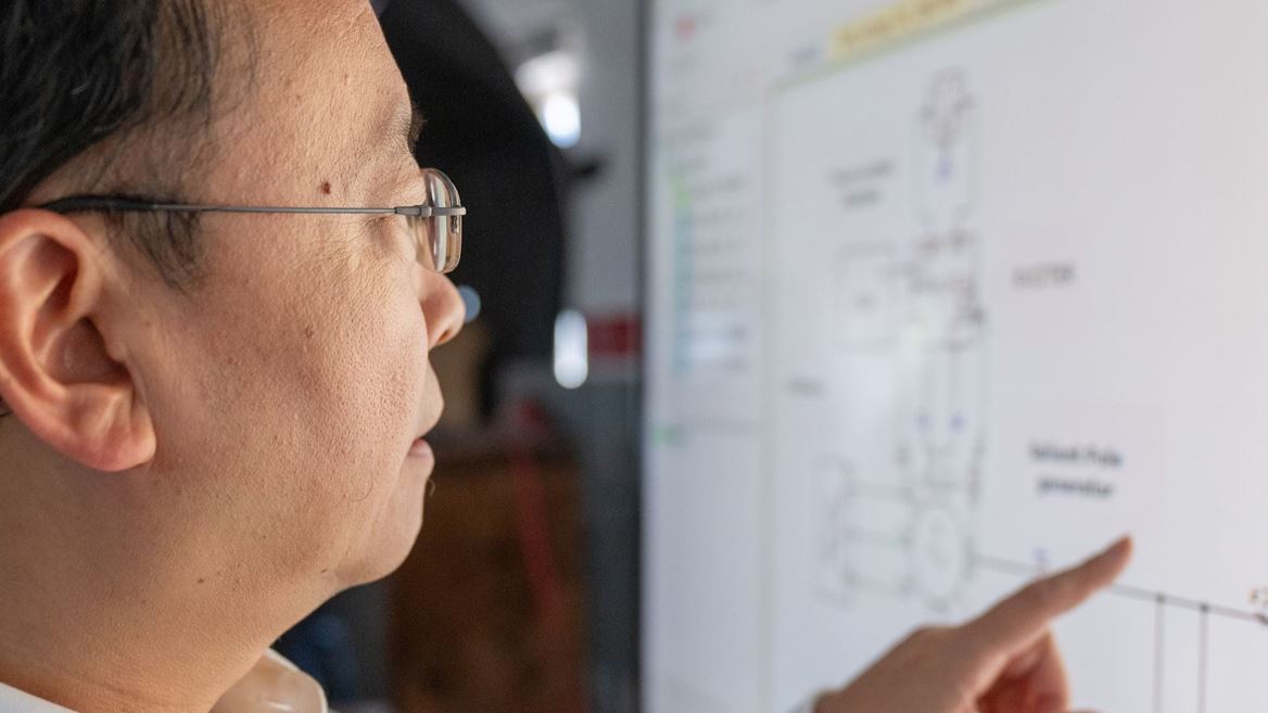 IMAGE DESCRIPTION Man standing next to a screen with diagrams