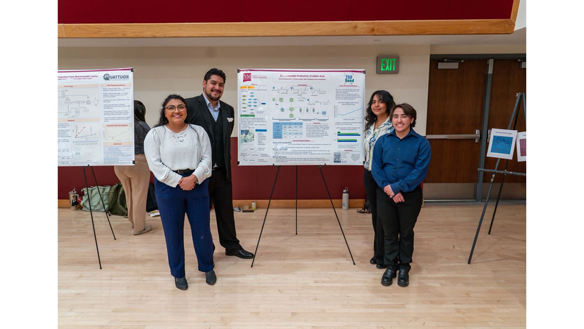 Description Four students stand in front of their poster presentation