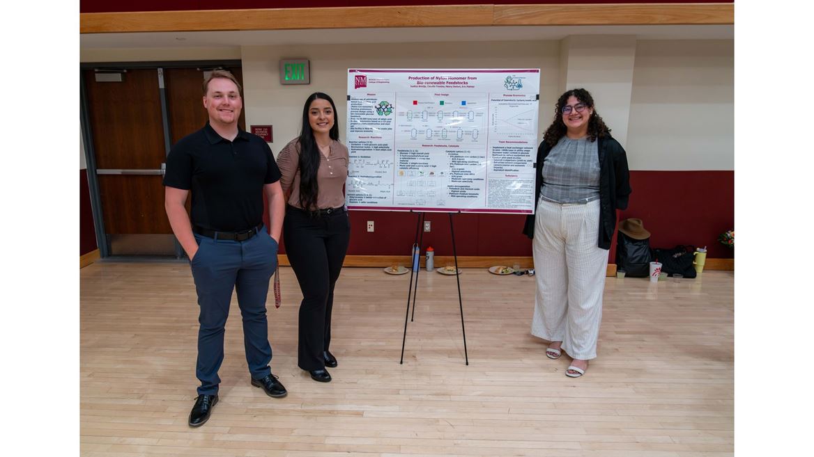 Description Three students stand in front of their poster presentation