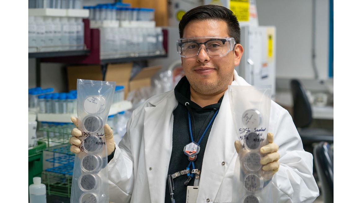 Description A researcher holds up two plastic packs full of Petri dishes that contain filters